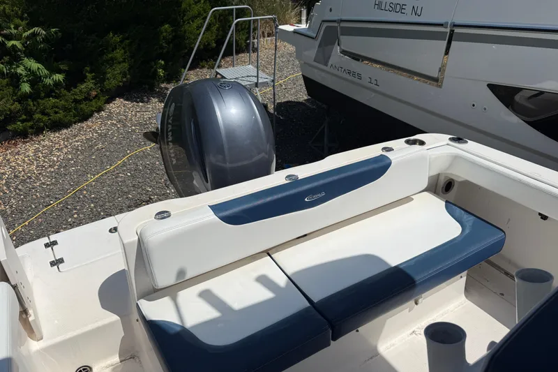 Slide: The Image of 2018 Robalo R222 Explorer boat interior with blue and white seating, parked outdoors. - 6