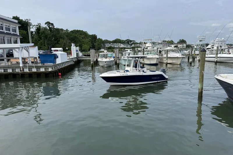 Slide: The Image of 2018 Robalo R222 Explorer boat docked in a marina with other vessels. - 4