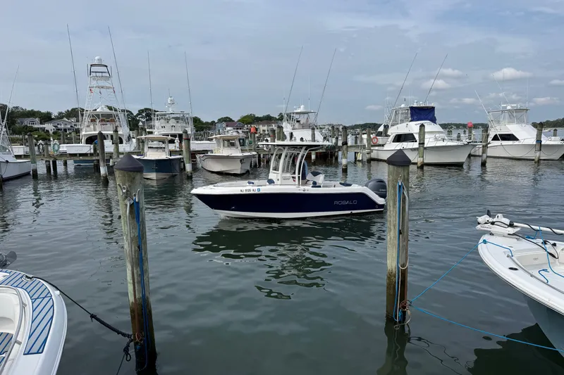 Slide: The Image of 2018 Robalo R222 Explorer boat docked in a marina with other vessels. - 2