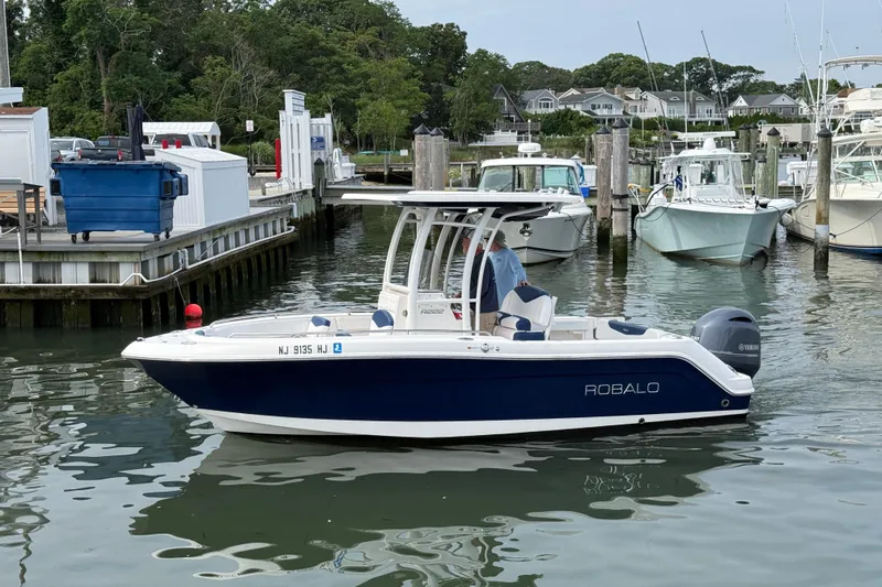 Slide: The Image of 2018 Robalo R222 Explorer boat docked in a marina, surrounded by other vessels. - 1