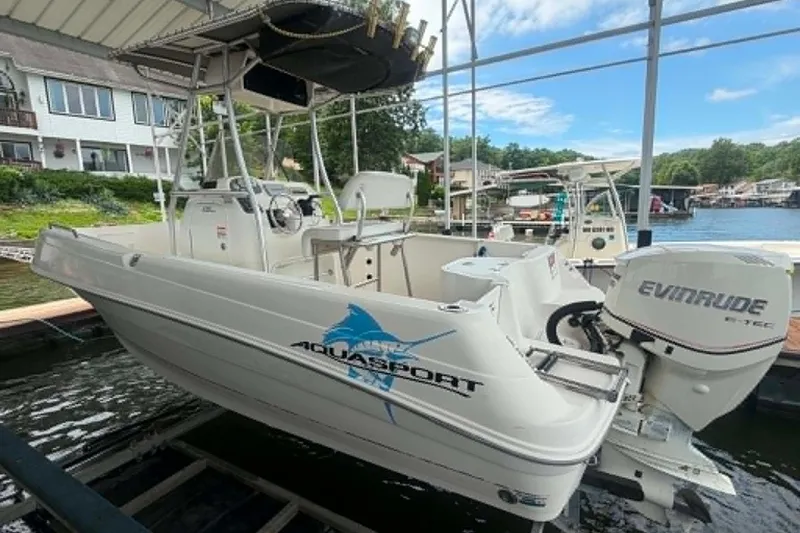 Slide: The Image of 2005 Aquasport 2100 Center Console boat docked with Evinrude engine, lakeside view. - 8
