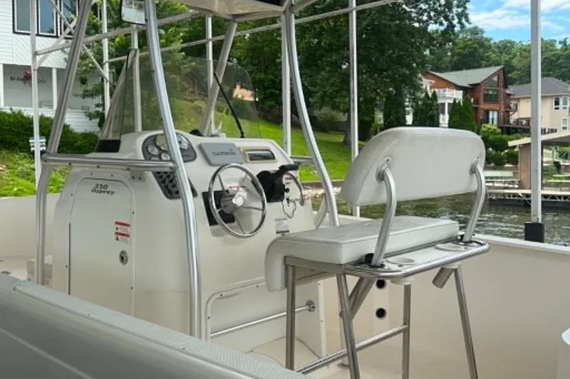Slide: The Image of 2005 Aquasport 2100 Center Console boat with steering wheel and seating, docked by a lake. - 9