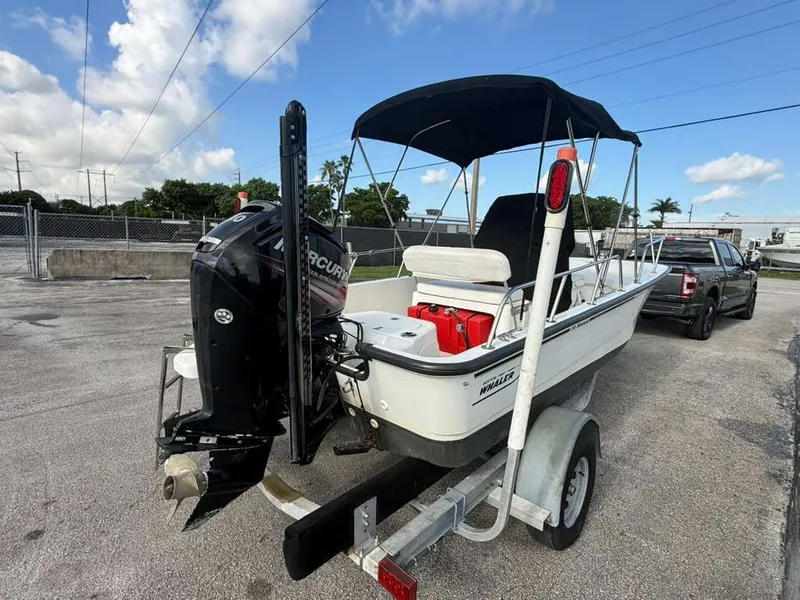 Slide: The Image of A 2016 Boston Whaler 170 Montauk on a trailer, featuring a black outboard motor and Bimini top. - 13