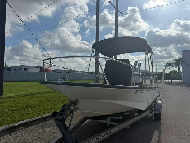 Slide: The Image of A 2016 Boston Whaler 170 Montauk on a trailer, featuring a Bimini top, under cloudy skies. - 15