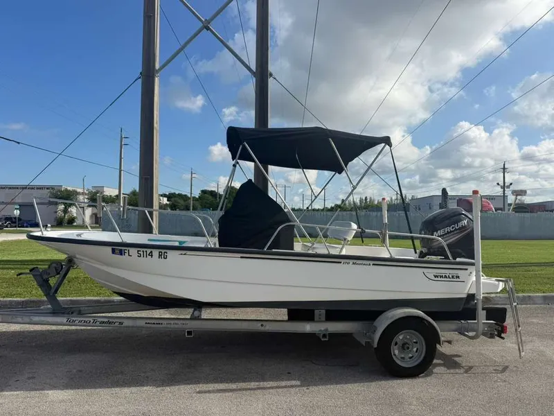 Slide: The Image of A 2016 Boston Whaler 170 Montauk on a trailer, featuring a black Bimini top. - 17