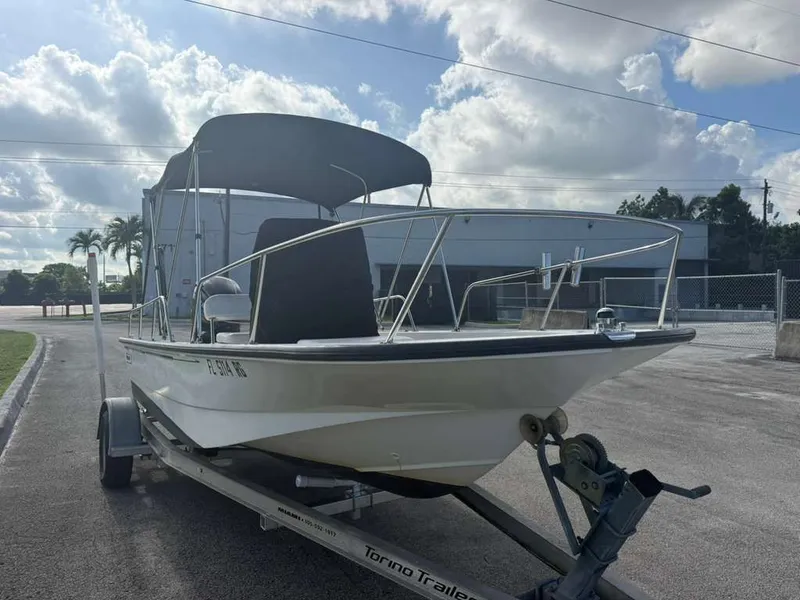 Slide: The Image of A 2016 Boston Whaler 170 Montauk on a trailer, featuring a Bimini top, in a parking lot. - 14