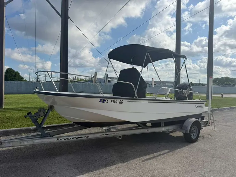 Slide: The Image of 2016 Boston Whaler 170 Montauk on a trailer, with black sunshade, parked outdoors. - 16