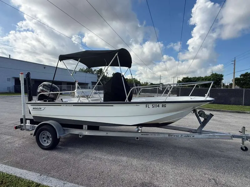 The Image of A 2016 Boston Whaler 170 Montauk on a trailer, featuring a black sunshade. - 0