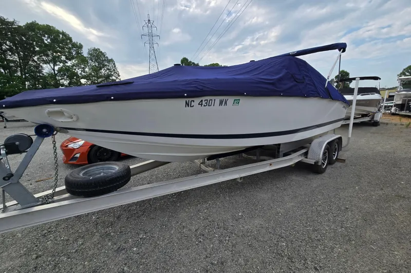 Slide: The Image of 2000 Cobalt 246 boat on trailer with blue cover, parked outdoors. - 2