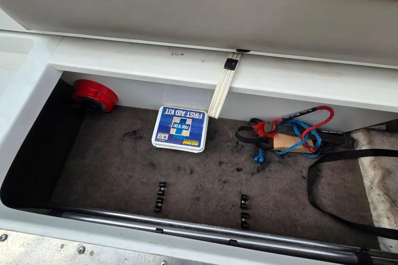 Slide: The Image of Storage compartment in a 2000 Cobalt 246 boat with first aid kit and ropes. - 28