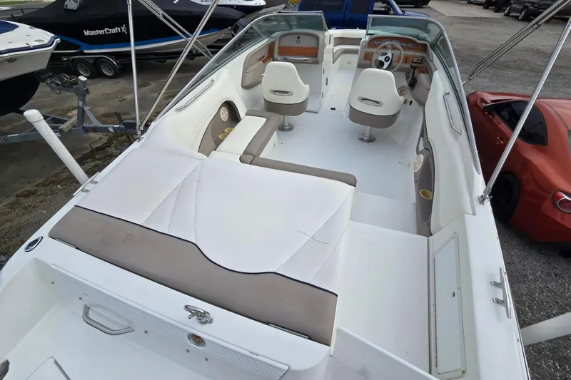 Slide: The Image of 2000 Cobalt 246 boat interior with white seating and dashboard, parked near other vehicles. - 12