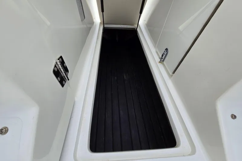 Slide: The Image of Interior view of a 2000 Cobalt 246 boat compartment with black flooring. - 26