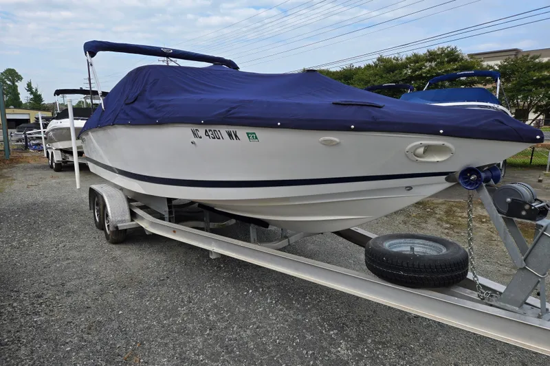 The Image of 2000 Cobalt 246 boat on trailer with blue cover, parked outdoors. - 0
