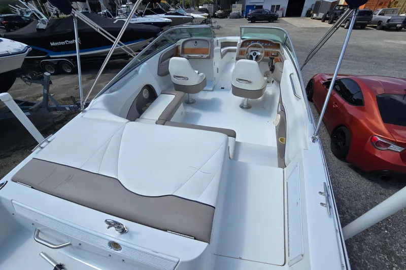 Slide: The Image of 2000 Cobalt 246 boat interior with white seating and dashboard, parked near a red car. - 18