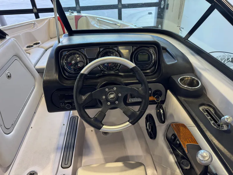 Slide: The Image of The image shows the cockpit of a 2011 Nautique Super Air Nautique 210 with a black steering wheel. - 25