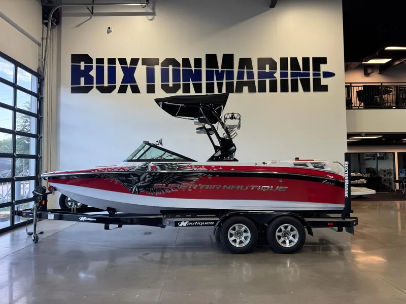 Slide: The Image of A red 2011 Super Air Nautique 210 boat on a trailer in a showroom. - 4