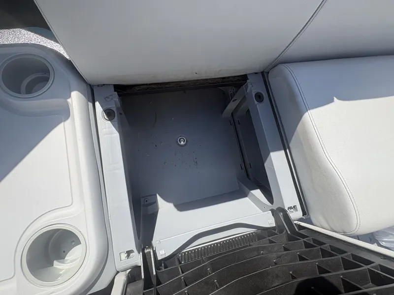 Slide: The Image of An open storage compartment on a boat with white upholstery and cup holders. - 21
