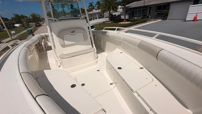 Slide: The Image of The image shows the deck of a 2015 Mako 284 Center Console boat. It features white upholstery and storage. - 20