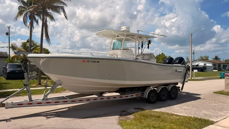 The Image of A 2015 Mako 284 Center Console boat on a trailer, parked in a residential area. - 0