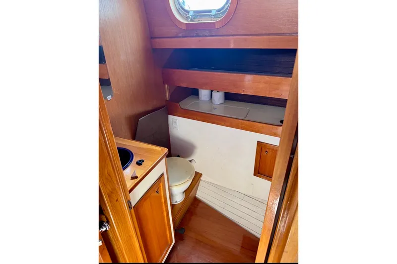 Slide: The Image of Interior of 1987 Custom Steel Cutter boat bathroom with wooden cabinetry and porthole. - 11