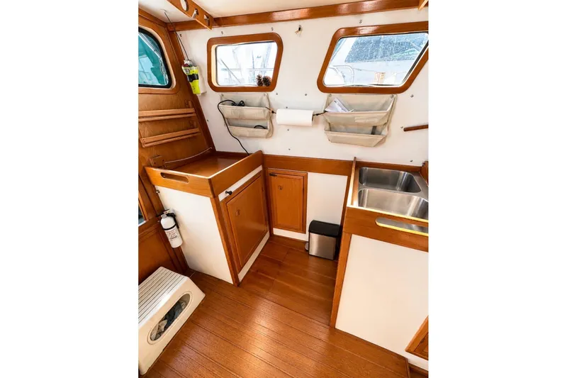 Slide: The Image of Interior of 1987 Custom Steel Cutter boat with wooden cabinetry and stainless steel sink. - 4