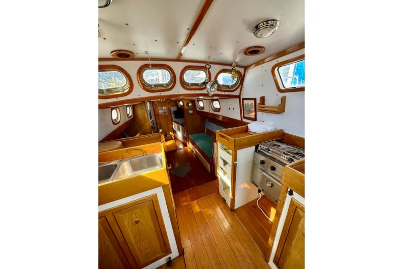 Slide: The Image of Interior of 1987 Custom Steel Cutter sailboat with wood finishes and compact kitchen area. - 7