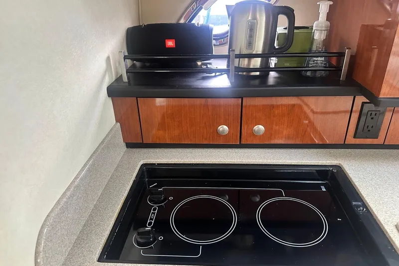 Slide: The Image of 2007 Sea Ray Sundancer 310 galley with stove, wooden cabinets, and countertop appliances. - 36