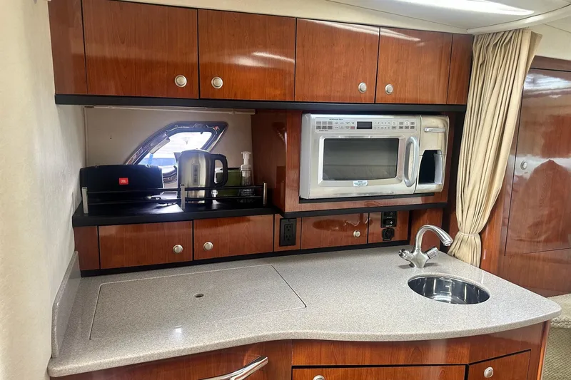 Slide: The Image of 2007 Sea Ray Sundancer 310 galley with microwave, sink, and wooden cabinetry. - 35