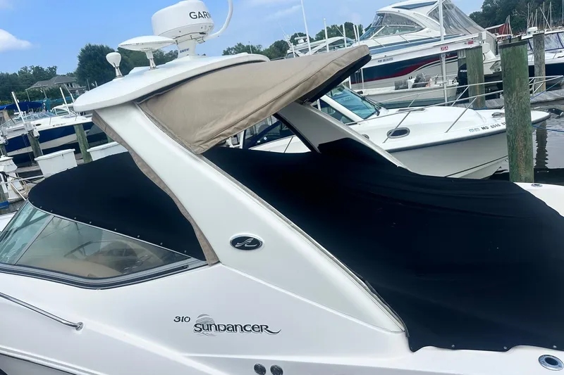 Slide: The Image of 2007 Sea Ray Sundancer 310 docked, featuring a black cover and beige canopy. - 8