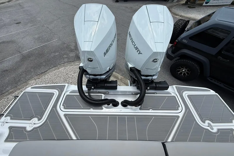 Slide: The Image of Twin Mercury outboard engines on a 2027 Monterey Elite 30 OB boat, parked near a vehicle. - 21