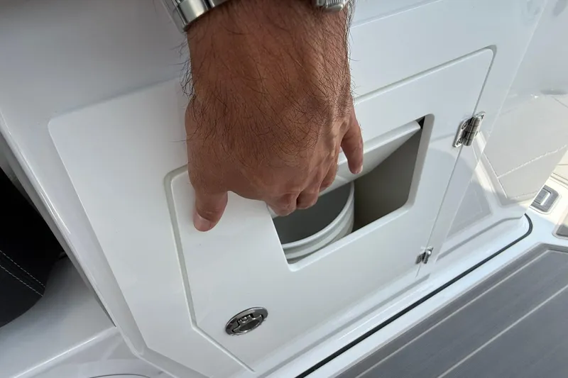 Slide: The Image of Hand opening storage compartment on 2027 Monterey Elite 30 OB boat. - 15