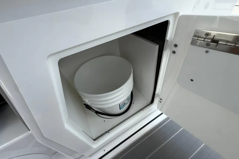 Slide: The Image of Storage compartment with a bucket inside the 2027 Monterey Elite 30 OB boat. - 14