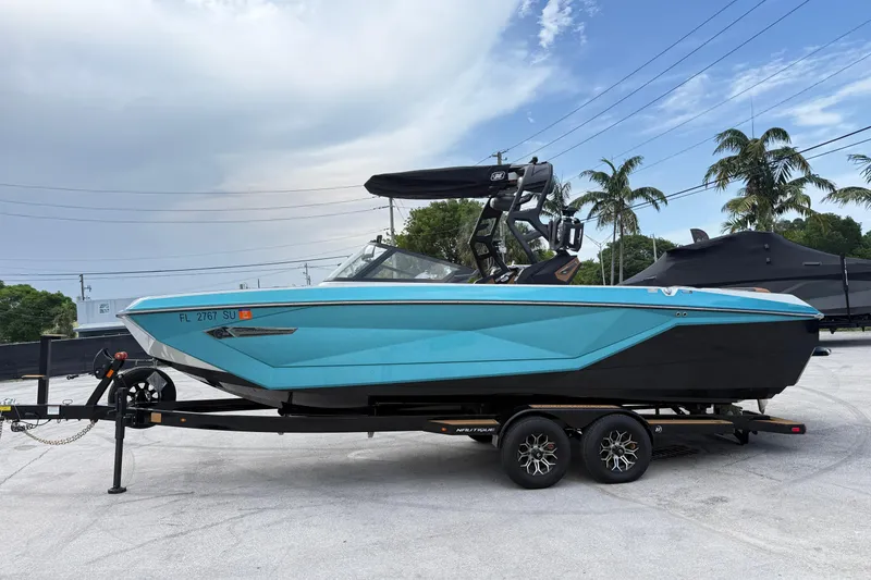 The Image of 2021 Nautique Super Air Nautique G25 Coastal Edition boat on trailer, blue and black design. - 0