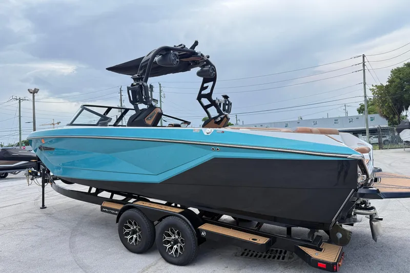 Slide: The Image of 2021 Nautique Super Air Nautique G25 Coastal Edition boat on trailer, blue and black design. - 12