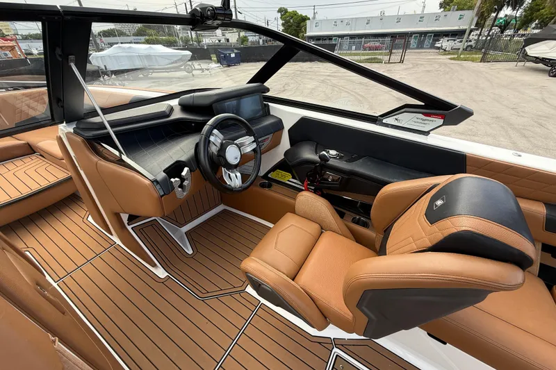 Slide: The Image of 2021 Nautique Super Air Nautique G25 Coastal Edition interior with tan leather seats and sleek dashboard. - 7
