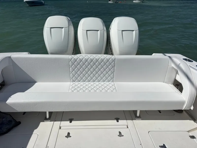 Slide: The Image of A white bench seat on a boat with three engines in the background, on calm water. - 3