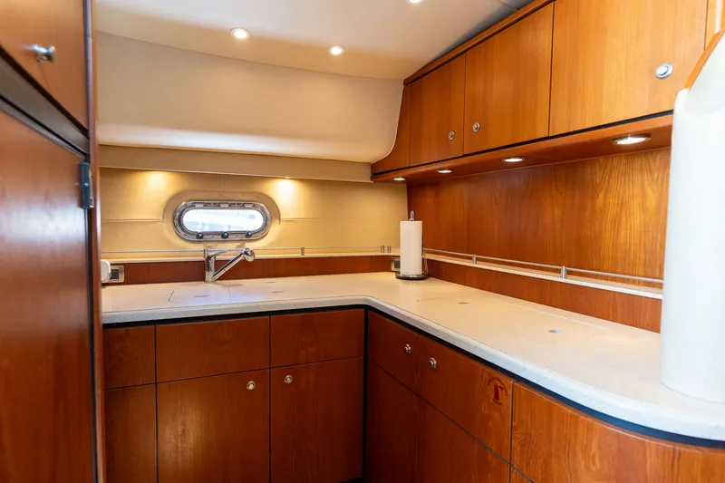 Slide: The Image of The 2008 Tiara Yachts 4300 Sovran's galley features wooden cabinets and a countertop. - 25