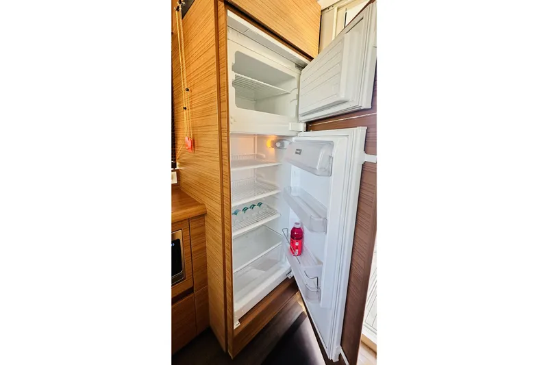 Slide: The Image of Open refrigerator inside 2021 Greenline 39 Hybrid yacht, showcasing spacious interior and wooden cabinetry. - 12