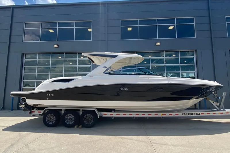 The Image of 2018 Sea Ray SLX 350 boat on trailer, parked outside a modern building. - 1