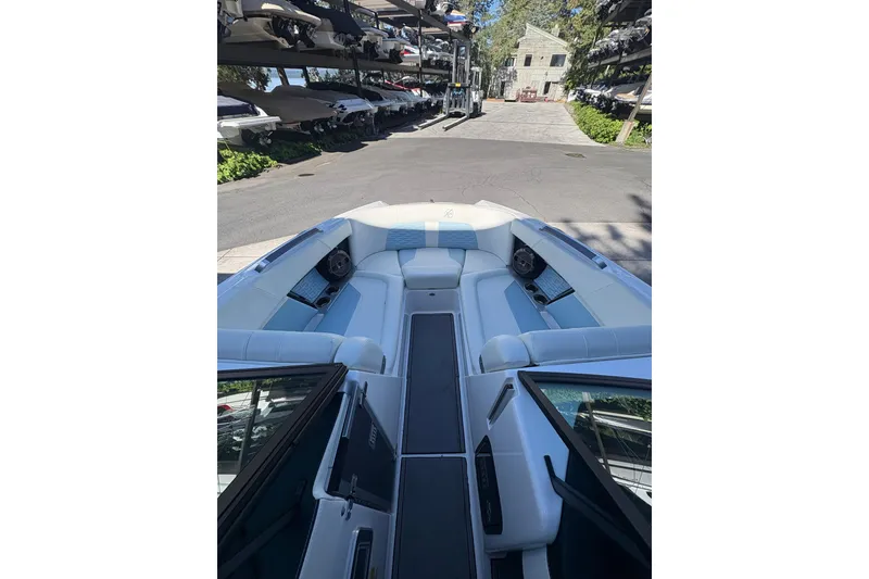 Slide: The Image of 2022 MasterCraft X24 boat interior with white seating, docked in a marina. - 2