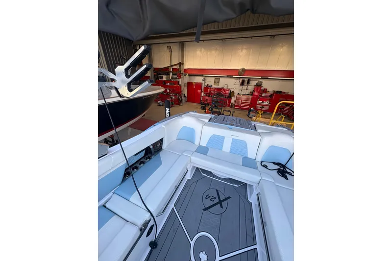 Slide: The Image of 2022 MasterCraft X24 boat interior in a workshop setting, showcasing seating and deck design. - 7