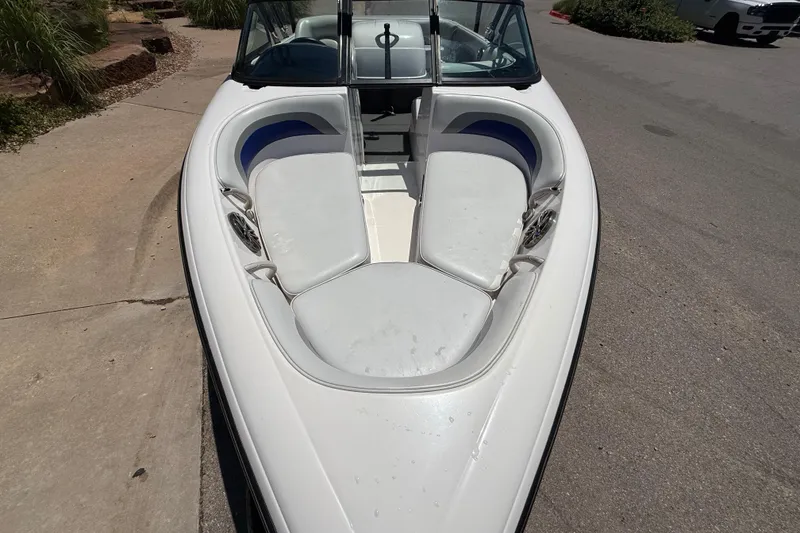 Slide: The Image of 2001 Moomba Outback boat with white seating and windshield, parked on pavement. - 4