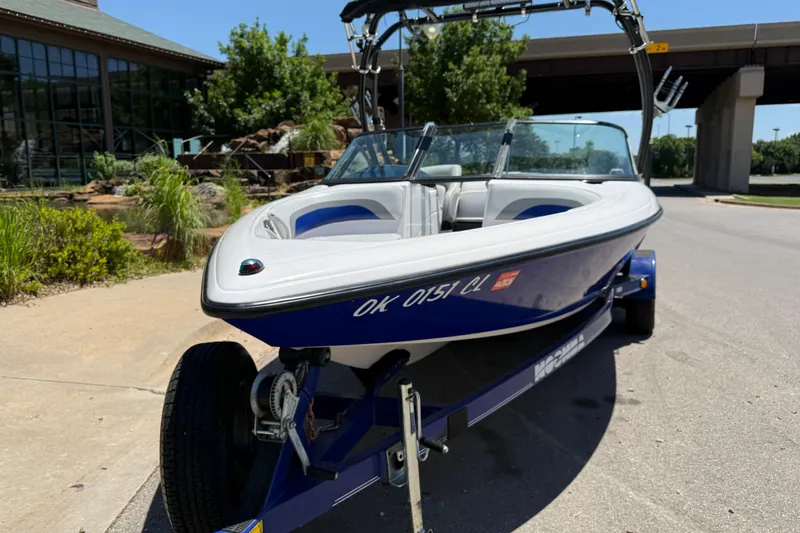 Slide: The Image of 2001 Moomba Outback boat on trailer, parked outdoors near a building and greenery. - 3
