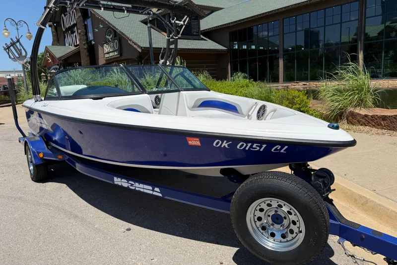 Slide: The Image of 2001 Moomba Outback boat on trailer, parked outside a building on a sunny day. - 2
