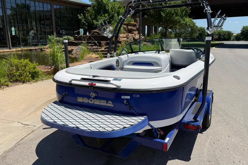 Slide: The Image of 2001 Moomba Outback boat in blue, parked near a pond with lush greenery. - 6