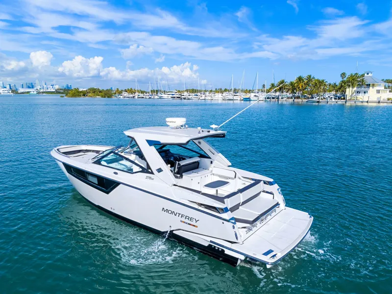 Slide: The Image of A white 2017 Monterey 378SE Super Express boat on calm water with a city skyline in the background. - 2