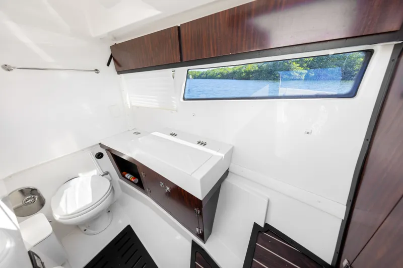 Slide: The Image of Interior view of a boat bathroom with toilet, sink, and window overlooking the water. - 21