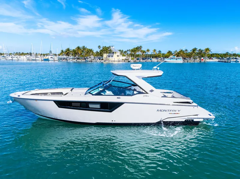 Slide: The Image of A white 2017 Monterey 378SE Super Express boat cruising on calm water with palm trees in the background. - 3