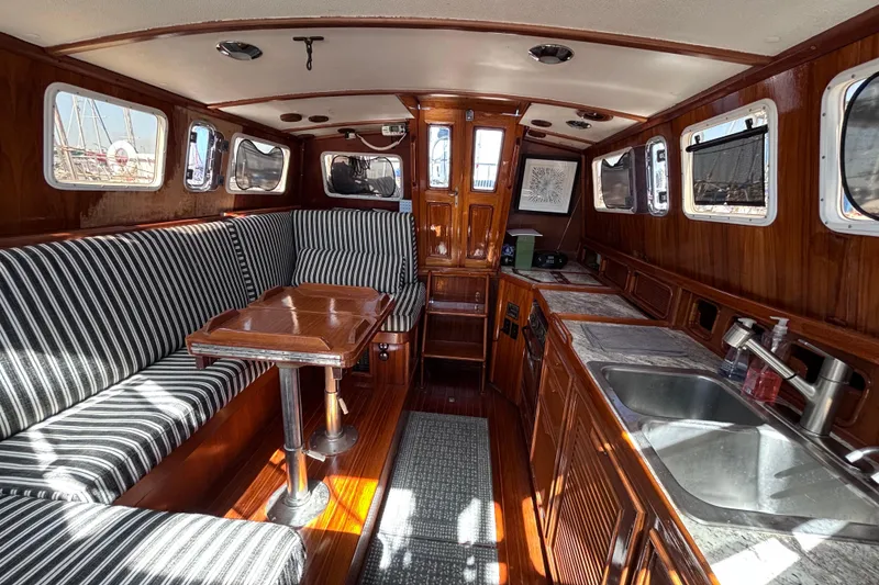 Slide: The Image of Interior of a 1978 Swift 33 yacht with striped seating, wooden table, and compact kitchen. - 17