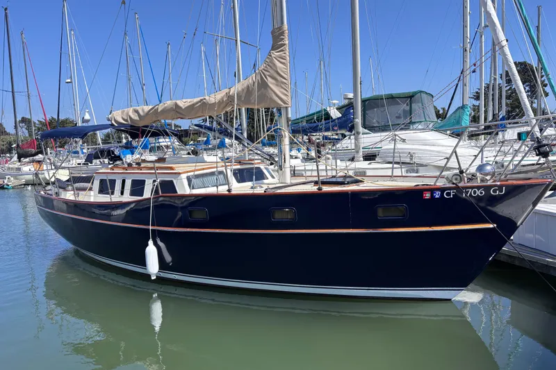 Slide: The Image of 1978 Swift 33 sailboat docked in marina, featuring sleek navy hull and beige sail cover. - 5